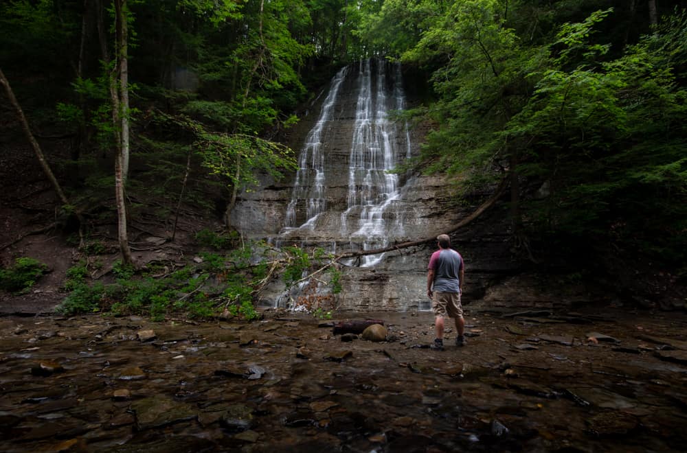 Man in front of waterfall at Grimes Glen in Naples, New York