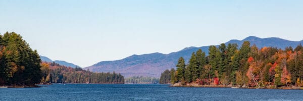 A panoramic image of Long Lake with fall foliage in the distance.