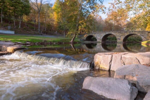 Small waterfall with Stone Arch Bridge in the background in the Catskills