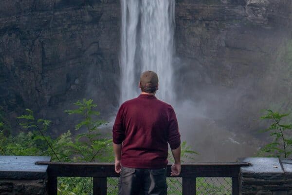 Man standing in front of a waterfall while looking for the best things to do in Ithaca NY