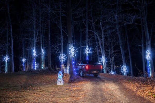 Truck driving through blue snowflake lights at ROC Lights at Victor Hills in the Finger Lakes