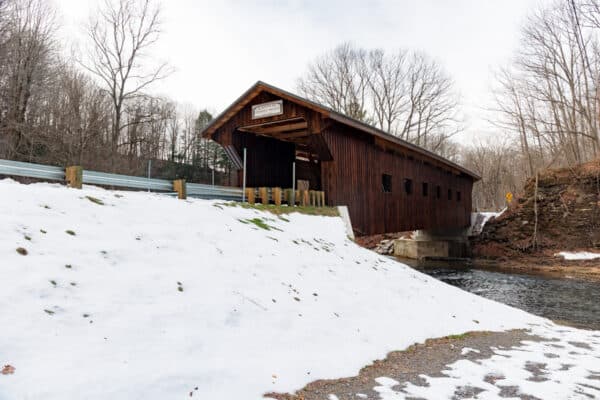 A side view of Cannon Covered Bridge in Wyoming County, NY surrounded by snow.