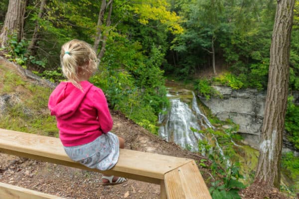Child sitting on railing at Delphi Falls Park in New York
