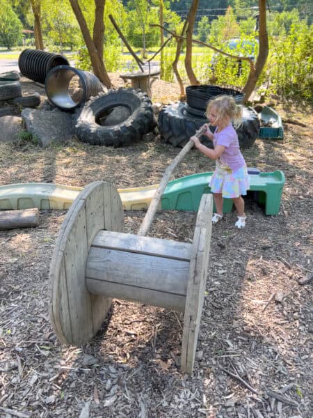 Girl playing with large items in the Anarchy Garden at the Ithaca Children's Garden in Tompkins County, NY