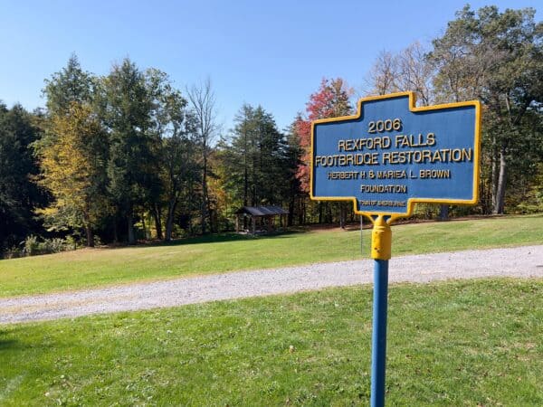 A blue and yellow sign marking the park around Rexford Falls.