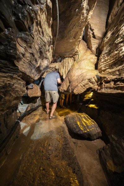 Man ducking under a stone formation inside Secret Caverns in Howe Caverns, New York